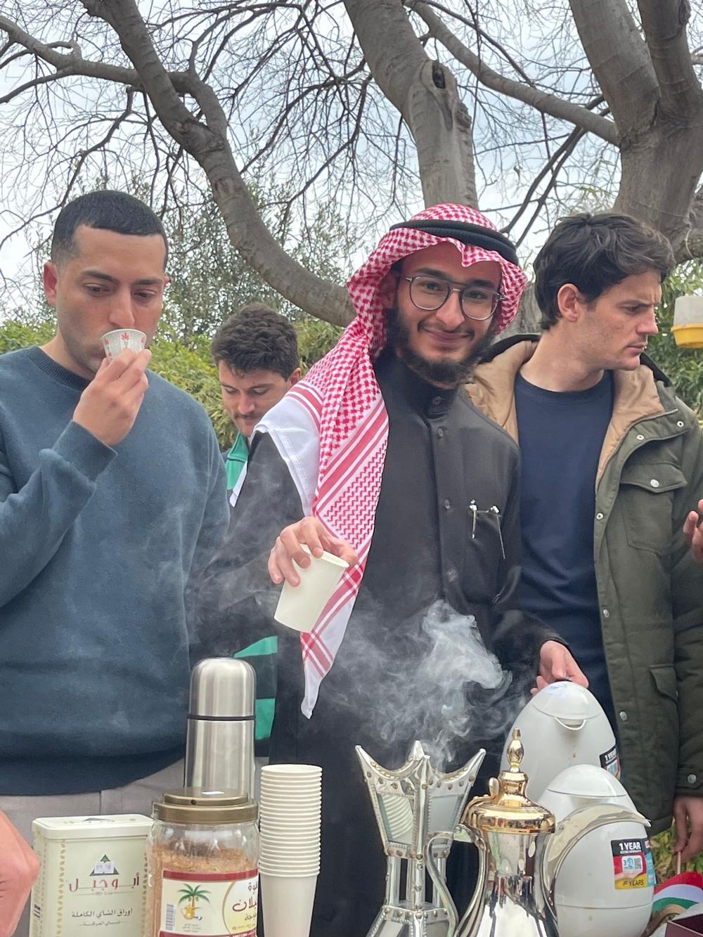 Aziz in traditional Gulf dress serving Arabic coffee at a campus event