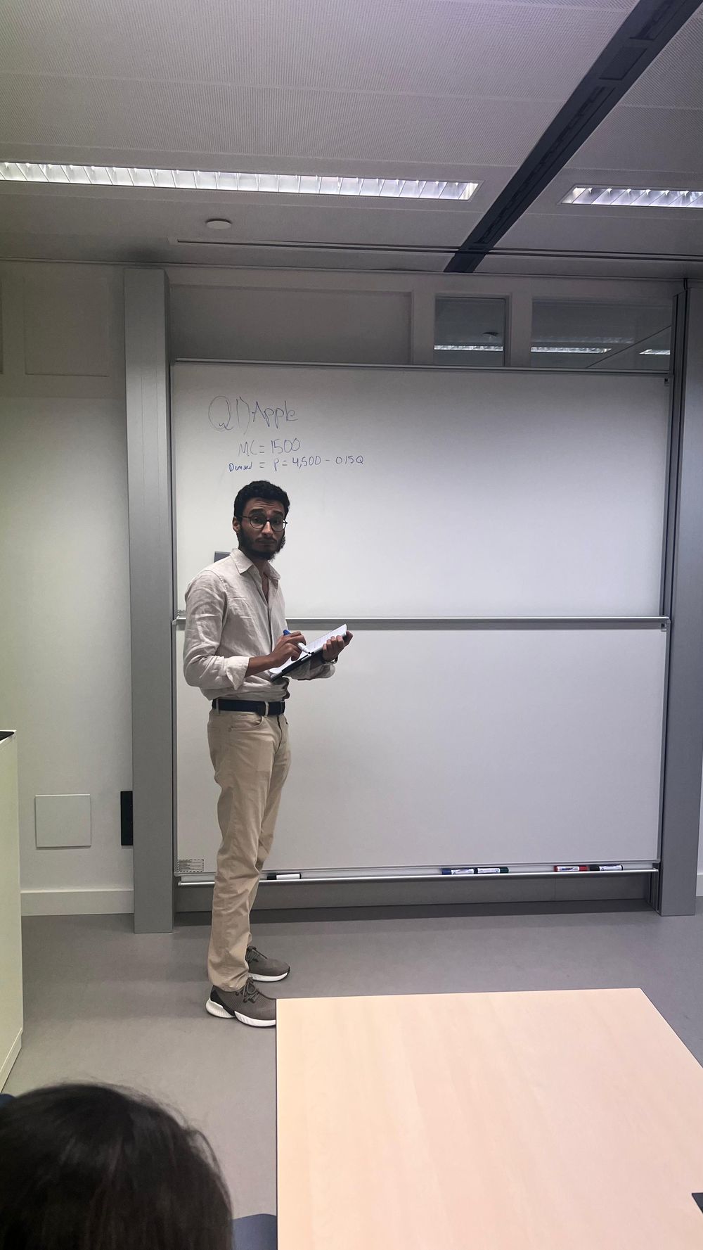 Aziz working through a pricing problem at a whiteboard in front of a class